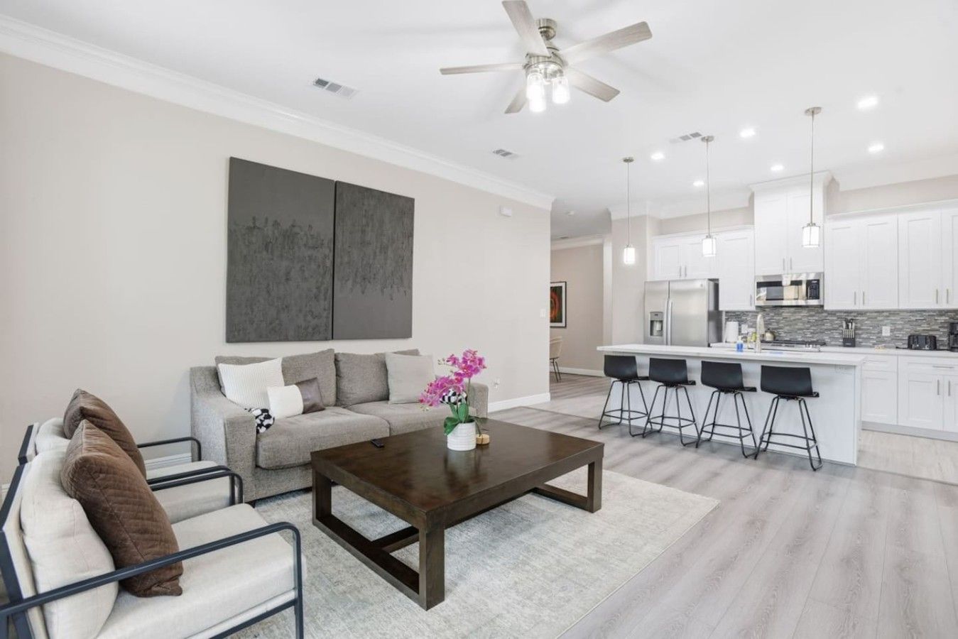 A modern living room with a sofa, coffee table, and a dining area with bar stools.