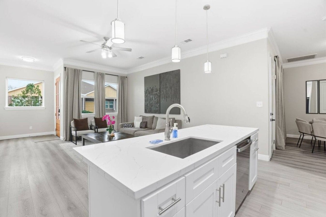 A modern kitchen with a large island, pendant lights, and a ceiling fan.