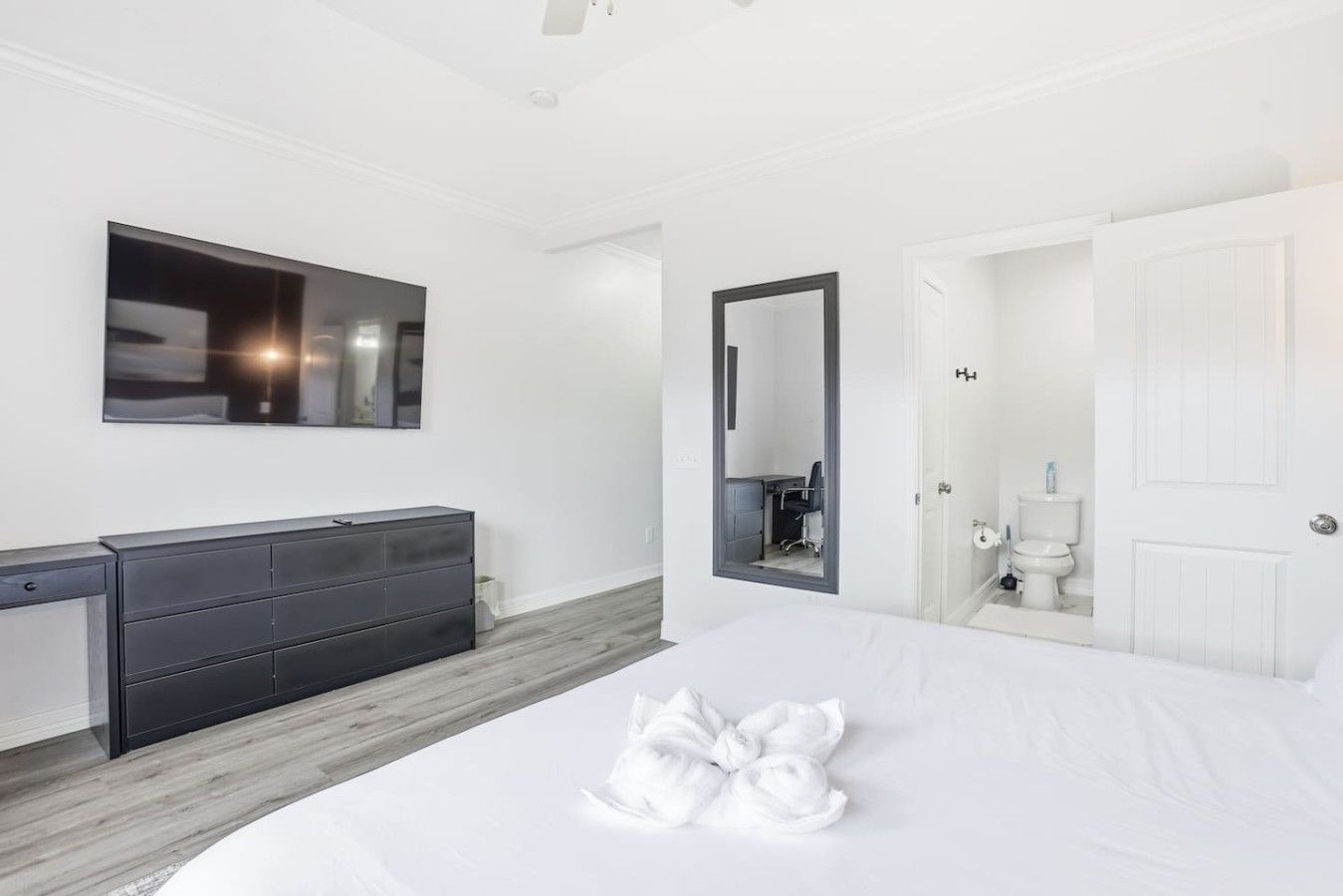 Habitación de hotel con cama, cómoda, espejo, puerta y un inodoro.
