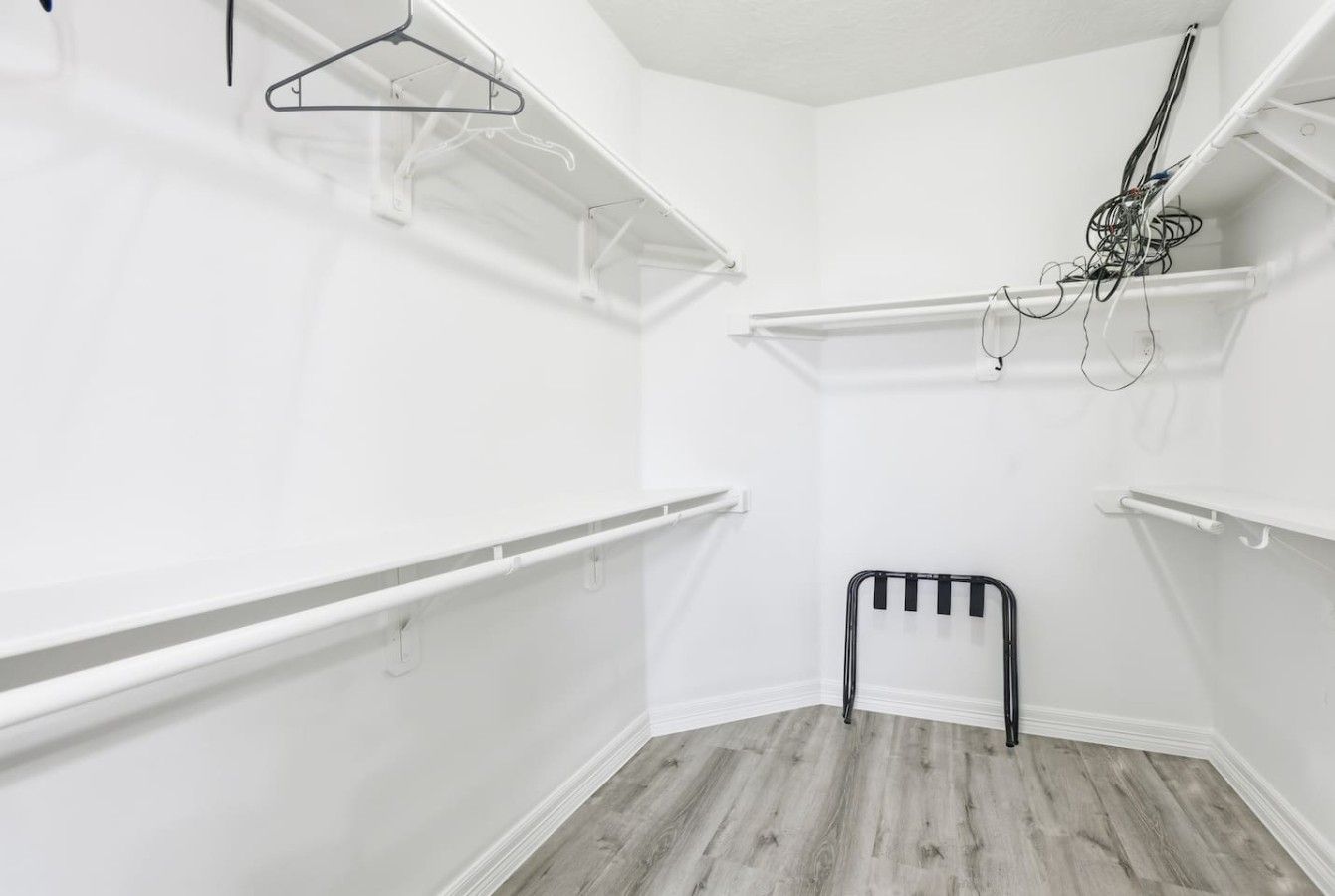 A room with white walls, a wooden floor, and multiple white shelves.