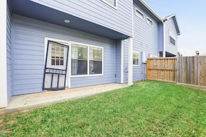 A residential building with a front door, windows, and a wooden fence.