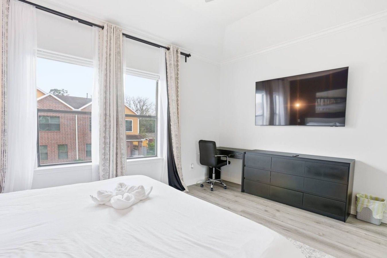 Una habitación de hotel con una cama, un escritorio y un ventanal grande.
