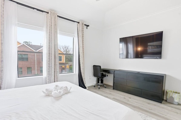 A hotel room with a bed, a desk, and a large window.