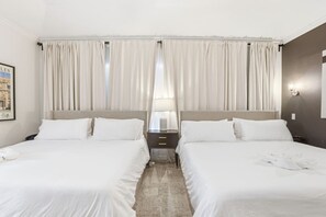 Habitación de hotel con dos camas, una mesita de noche, una lámpara y un cuadro en la pared.