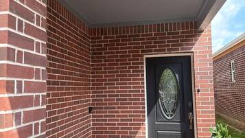 A brick exterior with a black door, a small overhang, and a visible window.
