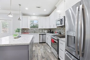 Una cocina moderna con gabinetes blancos, electrodomésticos de acero inoxidable y una isla grande.