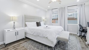 Un dormitorio moderno con cama, mesitas de noche, escritorio y ventilador de techo.