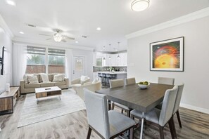 Una sala moderna con comedor, cocina y un ventanal grande.