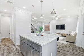A modern kitchen with a central island, pendant lighting, and a view into the living area. - SW Houston 1BR | King Bed, Sleeps 4 (Houston)