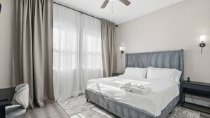 Ett hotellrum med en säng, ett skrivbord, en stol, en takfläkt och ett nattduksbord.