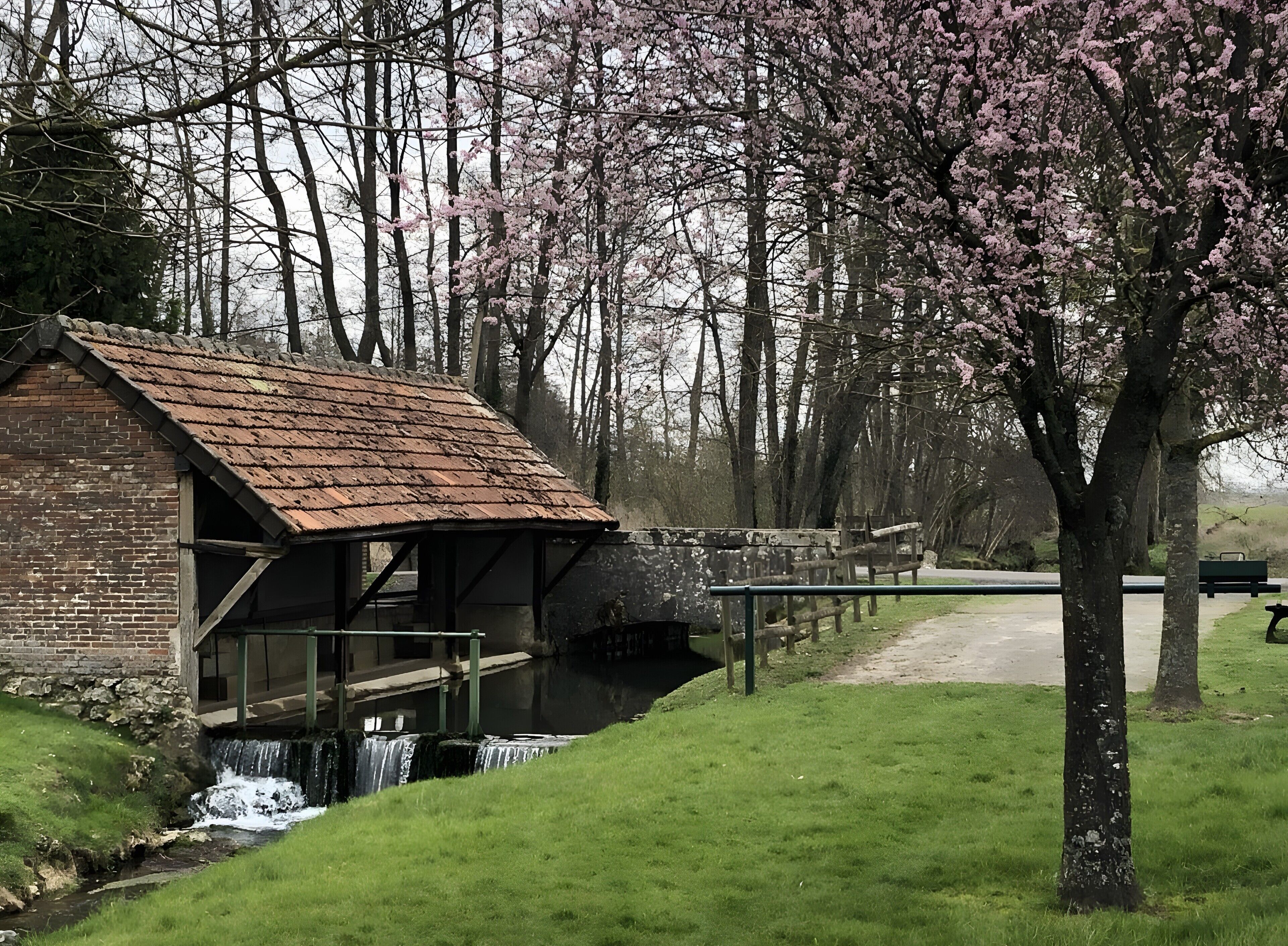 A rustic building with a brick exterior, a metal roof, and a small water feature in front.