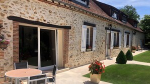 A stone house with a patio, outdoor seating, and a lawn.