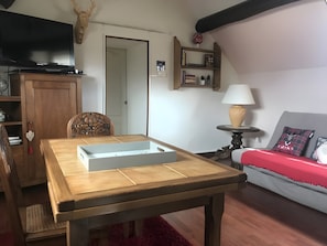 Una sala de estar con una mesa de madera, un sofá, un televisor y una estantería.