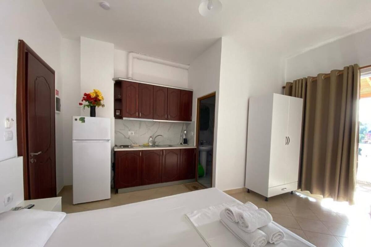 A hotel room with a bed, a small kitchenette, and a bathroom.