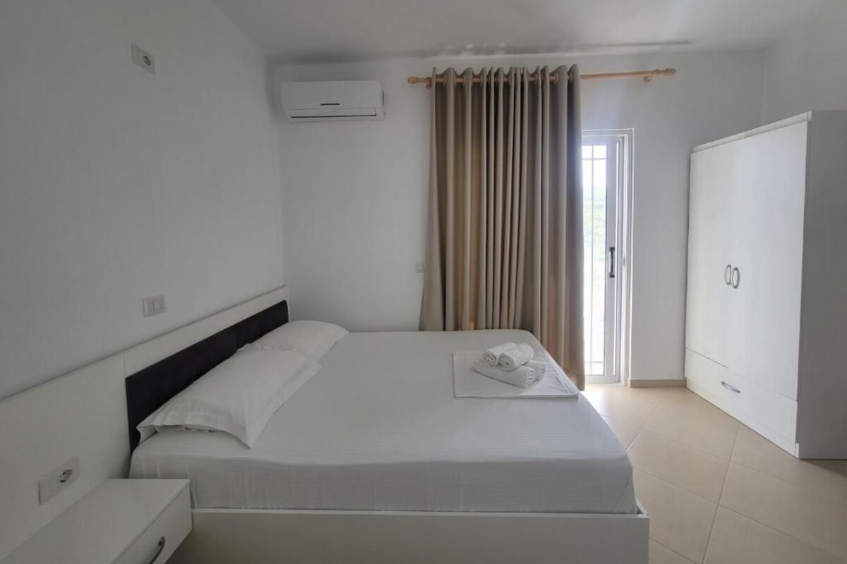A hotel room with a bed, a wardrobe, and a window with curtains.