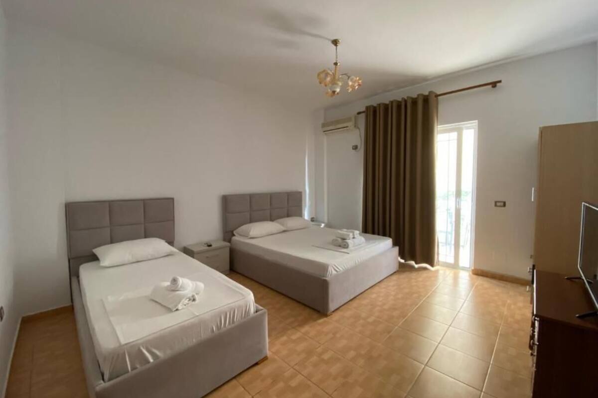 A hotel room with two beds, a wardrobe, a television, and a ceiling fan.