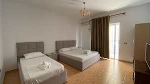 Une chambre d’hôtel avec deux lits, une armoire, une télévision et un ventilateur de plafond.