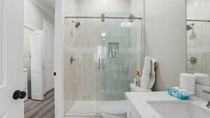 Une salle de bain moderne avec une douche à parois de verre, des toilettes et un lavabo équipé de produits de toilette.