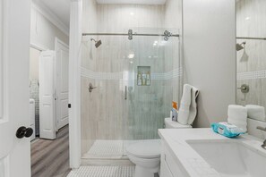 Une salle de bain moderne avec une douche à parois de verre, des toilettes et un lavabo équipé de produits de toilette.