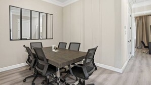Un salón de conferencias con una mesa rectangular, seis sillas y un espejo grande en la pared.