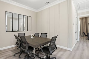 Een vergaderruimte met een rechthoekige tafel, zes stoelen en een grote spiegel aan de muur.