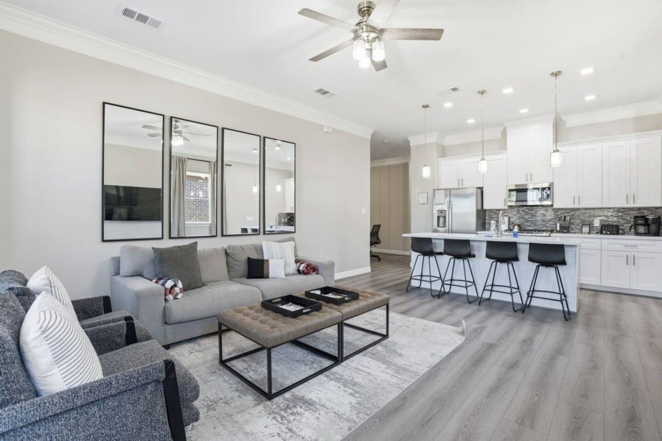 A modern living room with a sofa, coffee table, and a kitchen area with bar stools.