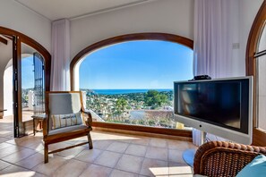 A balcony with a TV, a chair, and a view of the sea. - Villa rental in Moraira, MIMOSA (Moraira)