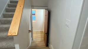 Una escalera estrecha con barandillas de madera y escalones alfombrados que conducen a una puerta.