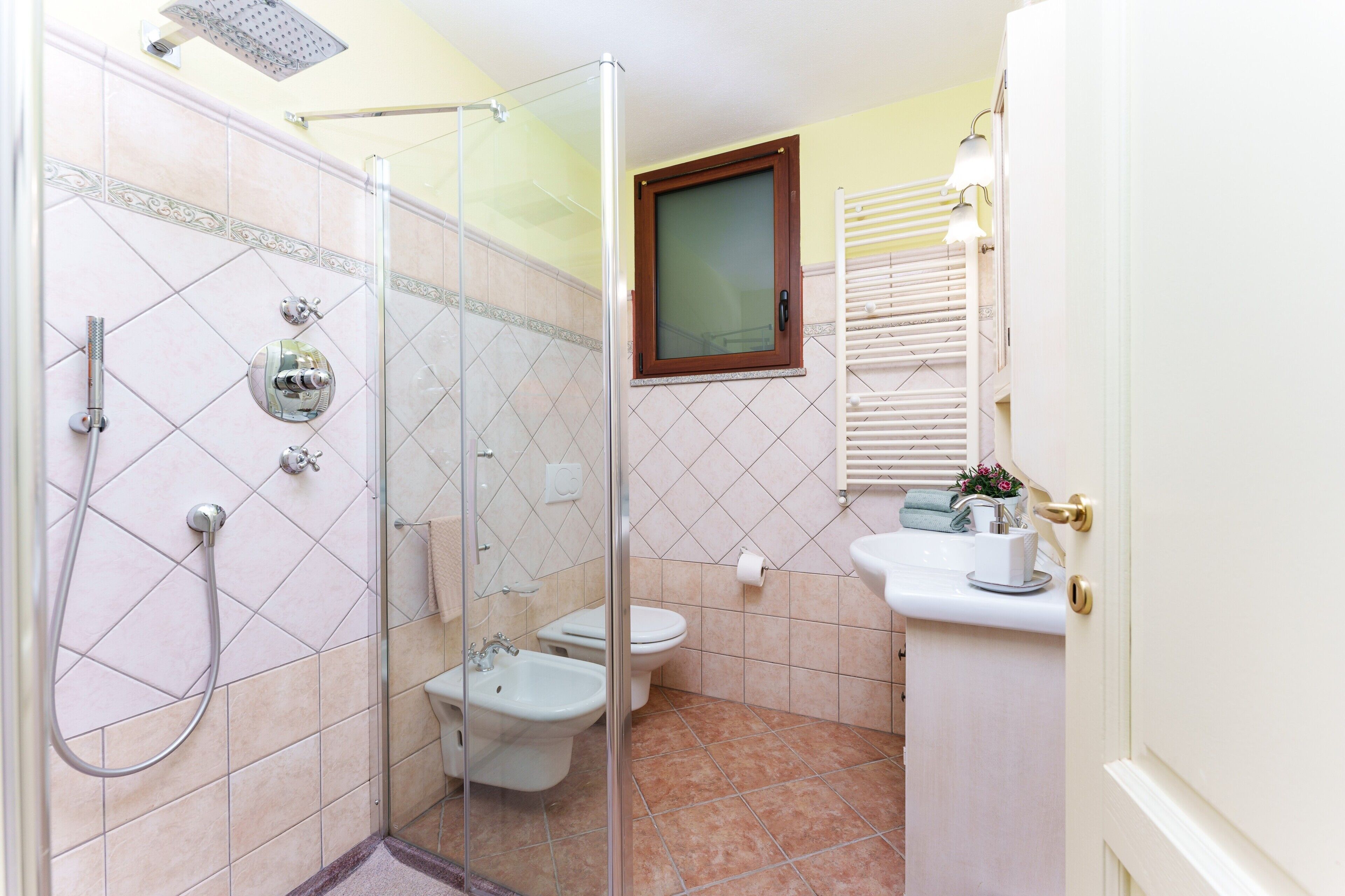 A bathroom with a shower, bidet, toilet, and sink.