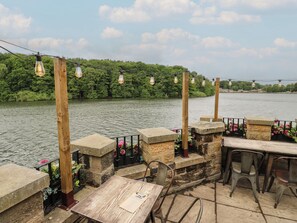 Un espace extérieur aménagé avec des tables et des chaises en pierre, offrant une vue sur une rivière.