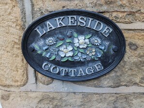Une plaque métallique portant l’inscription « LAKESIDE COTTAGE » et ornée de motifs floraux.