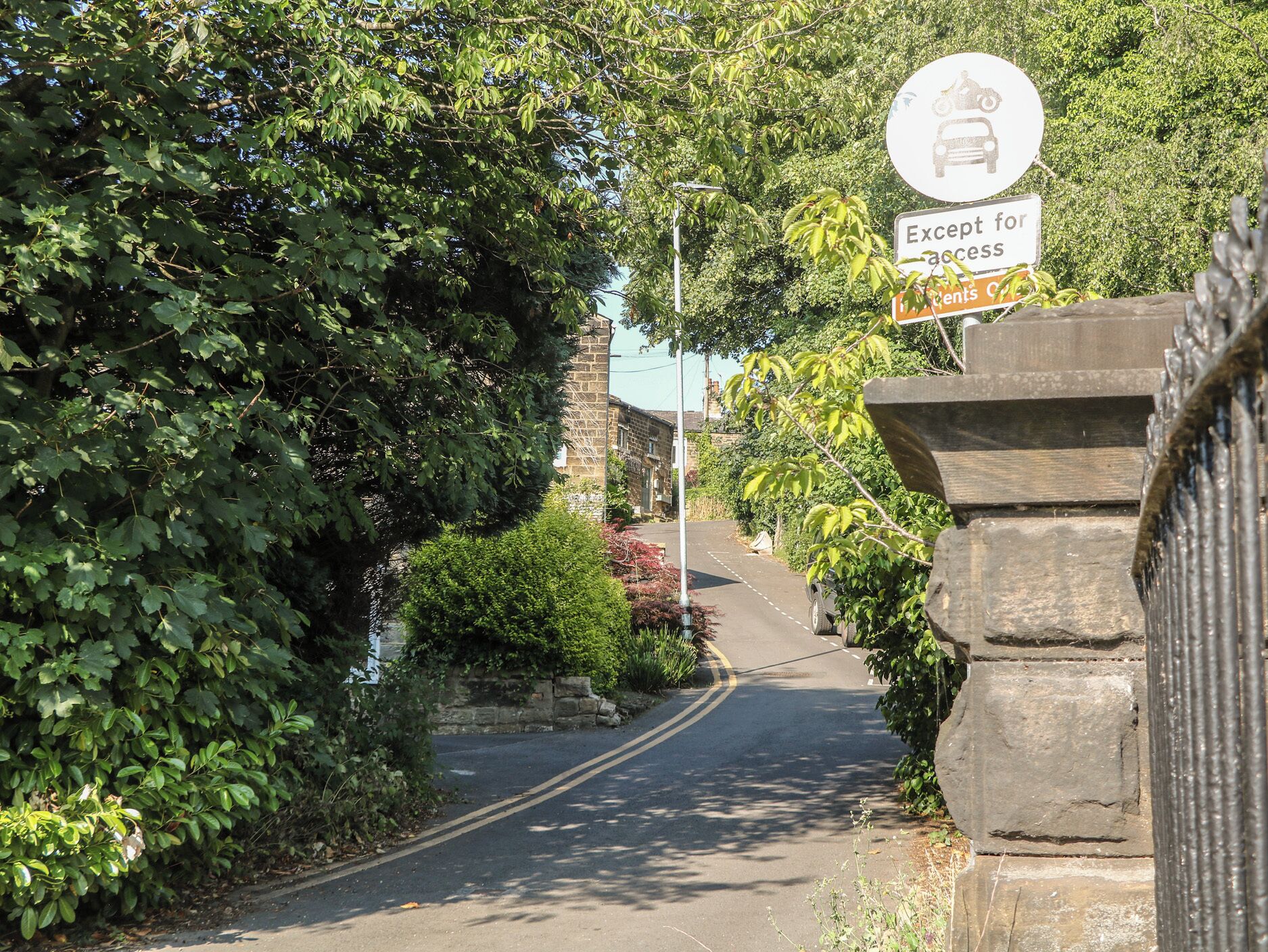 A narrow road with a sign indicating access for residents only.