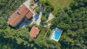 Vue aérienne d’une propriété résidentielle dotée d’une piscine, de plusieurs bâtiments et d’un espace vert environnant.
