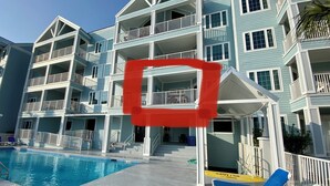 A multi-story hotel with balconies, a swimming pool, and lounge chairs. - BEAUTIFUL GULF VIEW 2B/2B BALCONY OVER THE POOL,EASY BEACH ACCESS (Orange Beach)