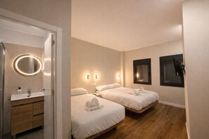 Habitació d'hotel amb bany, dos llits, un mirall i llums penjades a la paret.