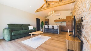 Un soggiorno moderno con un divano verde, un tavolino in legno e una zona cucina con sgabelli da bar.