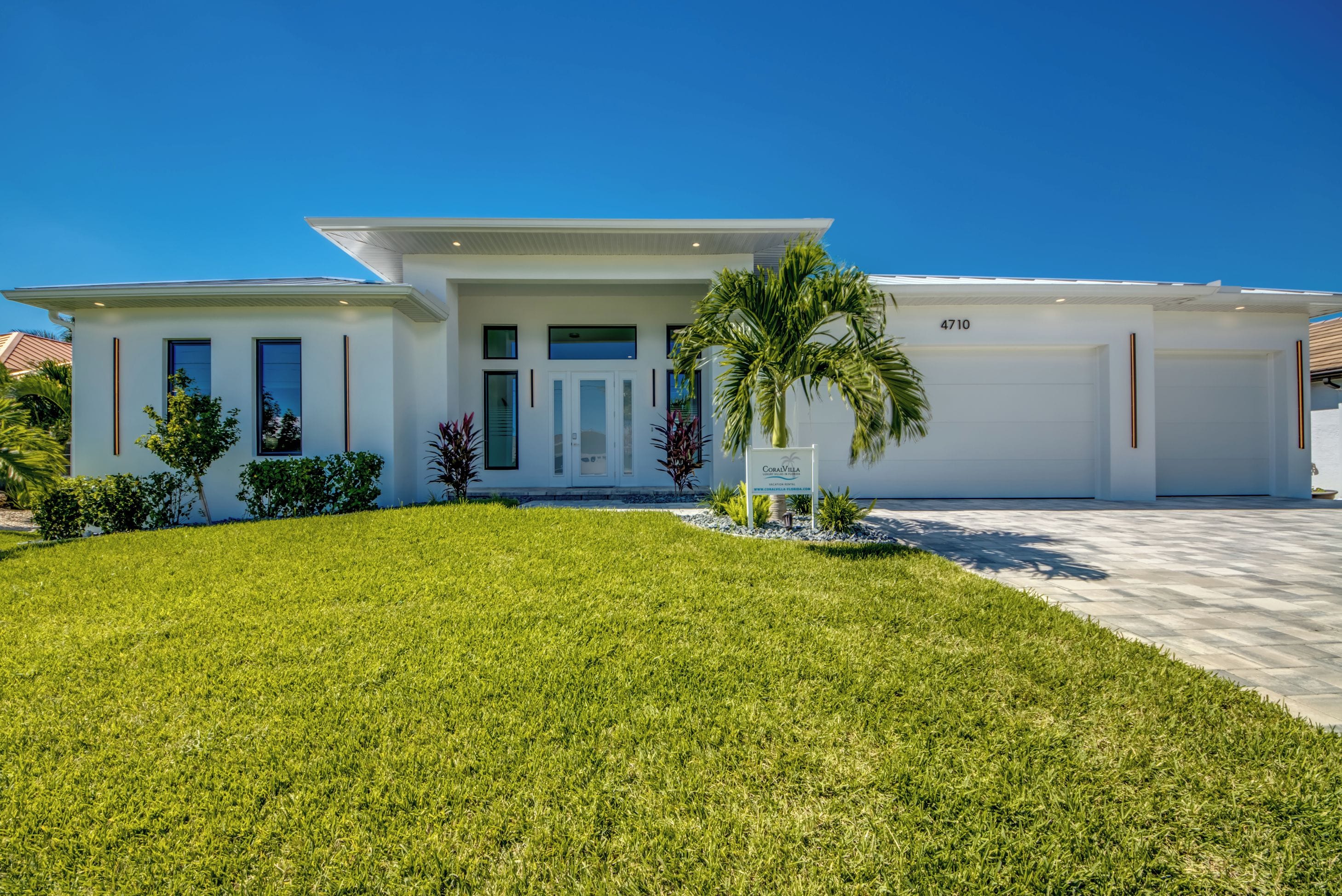 A modern two-story house with a well-maintained lawn and a palm tree in the front yard.