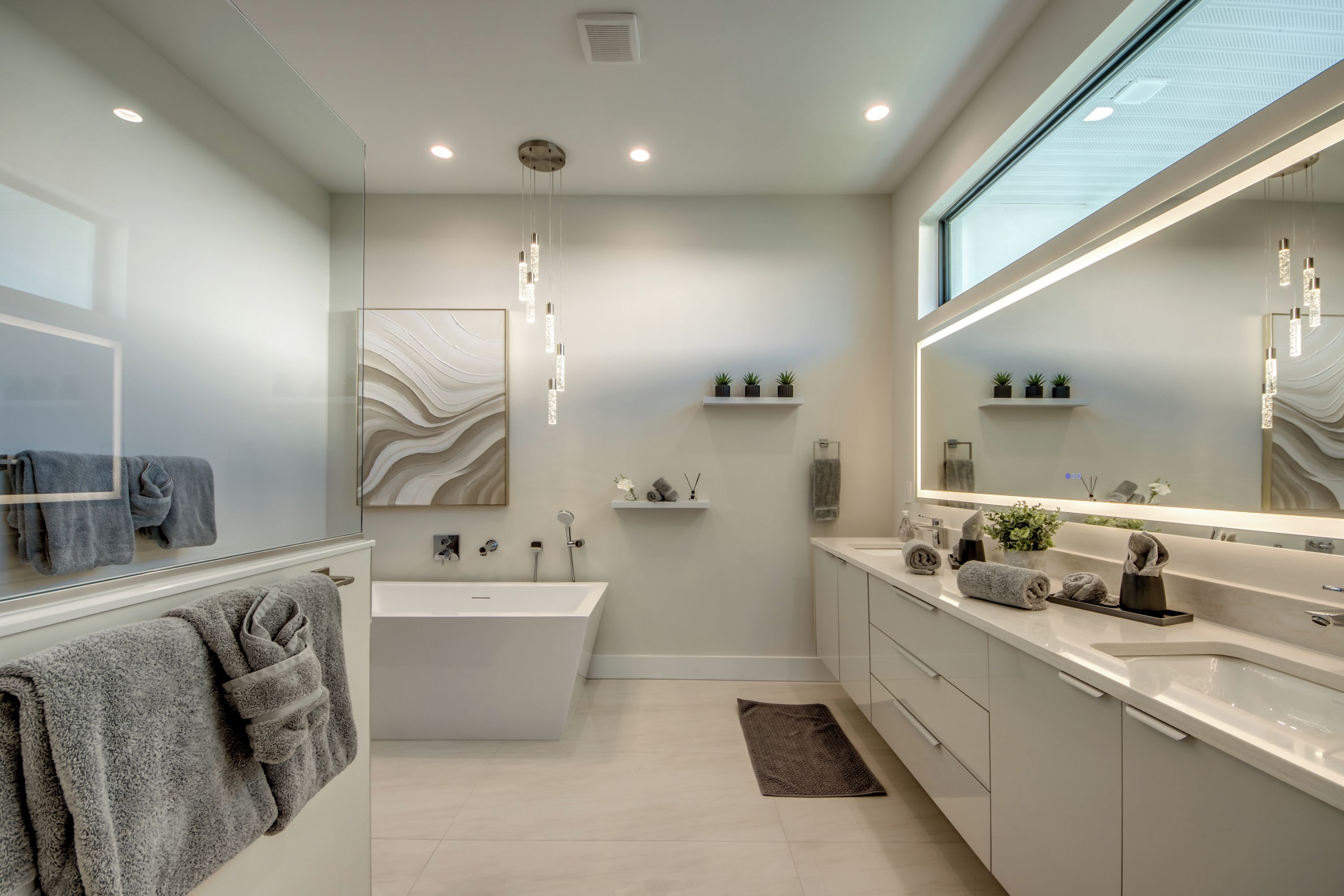 Un baño moderno con una bañera, un espejo grande y un lavamanos.