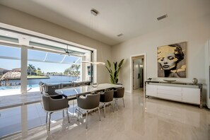 A modern kitchen with a dining area, large windows, and a view of a pool. - Villa Aesthetic View - great view, on water, pool, spa, gulf access (Cape Coral)