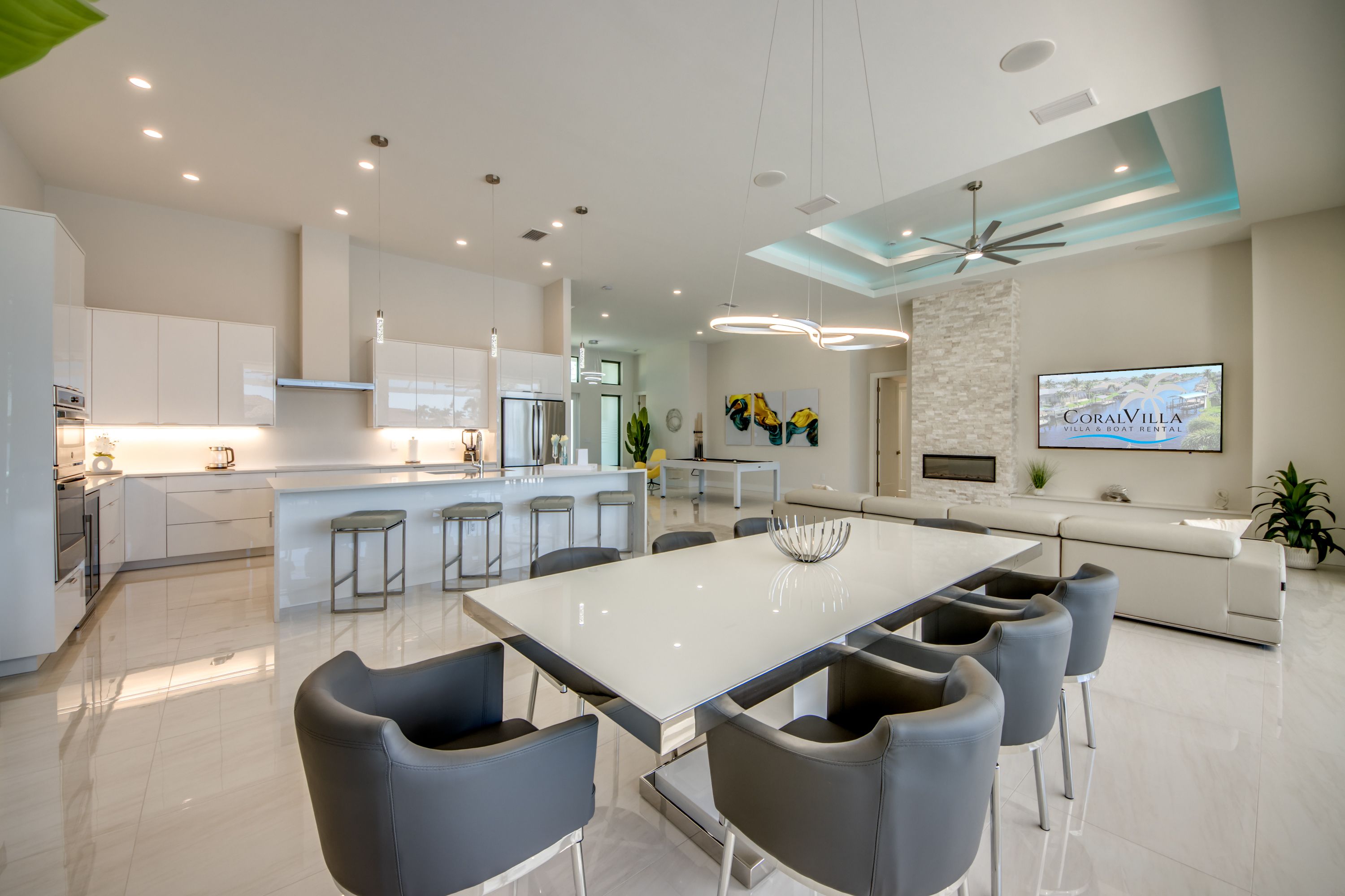 A modern kitchen with white cabinetry, stainless steel appliances, and a central island with bar stools.