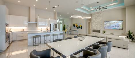 Cocina moderna con armarios blancos, electrodomésticos de acero inoxidable y una isla central con taburetes de bar.