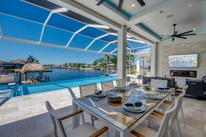 Una villa moderna con piscina cubierta de vidrio, zona de comedor con vistas a la piscina y un televisor que muestra 'CoralVilla'.