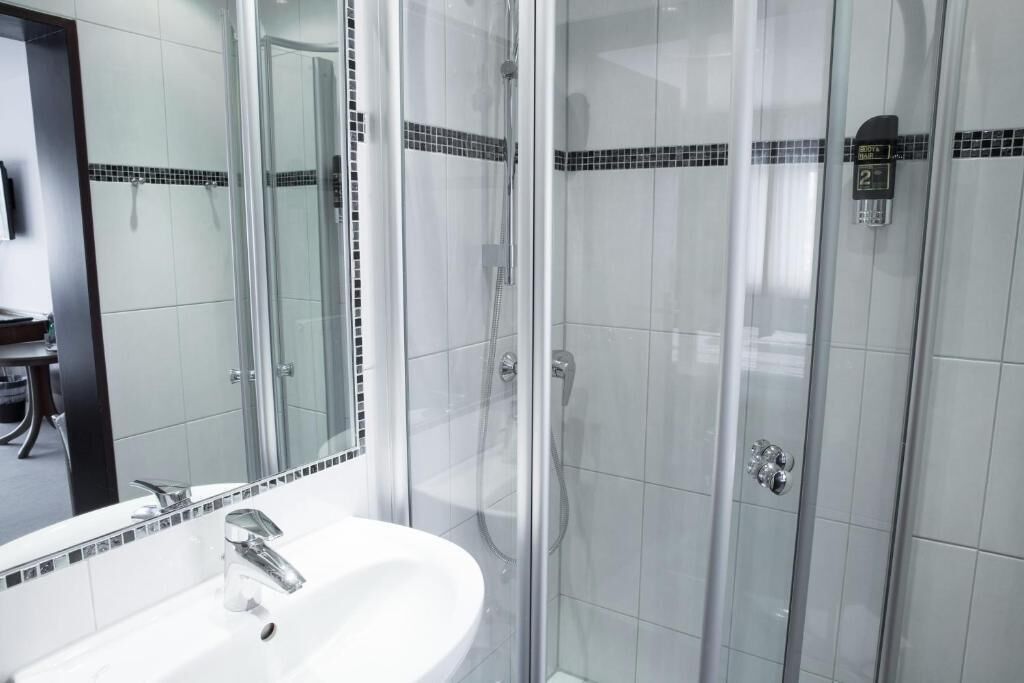 A modern bathroom with a glass-enclosed shower, a white sink, and a mirror.