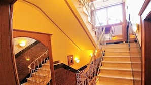 A grand staircase with a wooden handrail and a glass railing, leading to an upper floor. - Hotel Wilms (Cologne)