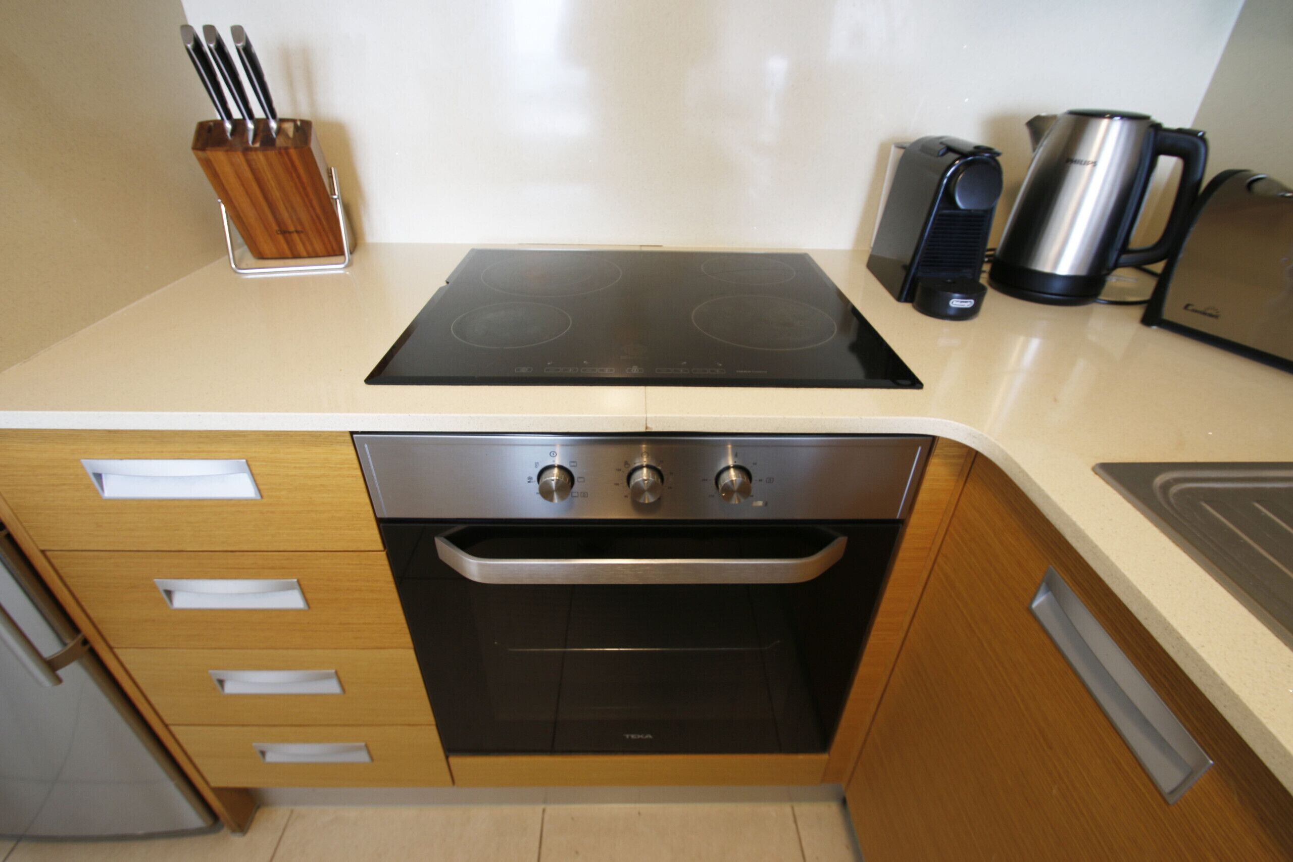 A kitchen with a built-in oven, a coffee maker, and a kettle.