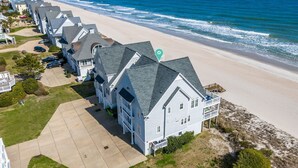A beachfront property with a row of houses, a sandy beach, and the ocean. - Oceanfront | Pet Friendly | Elevator | Hot Tub | Pool Access (North Topsail Beach)