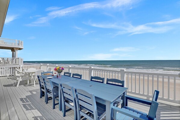 A deck with a table and chairs overlooking the ocean.