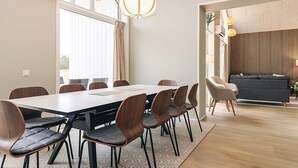 Una sala de reuniones moderna con una mesa larga y sillas, un sofá al fondo y una alfombra estampada.