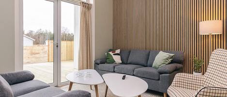 A modern living room with a grey sofa, a white coffee table, and a patterned rug.