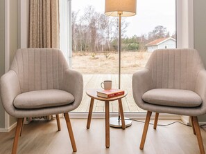 Two armchairs facing a window with a view of a yard and a lamp on a small table. - 5 Star Holiday Home in Laeso (Læsø)